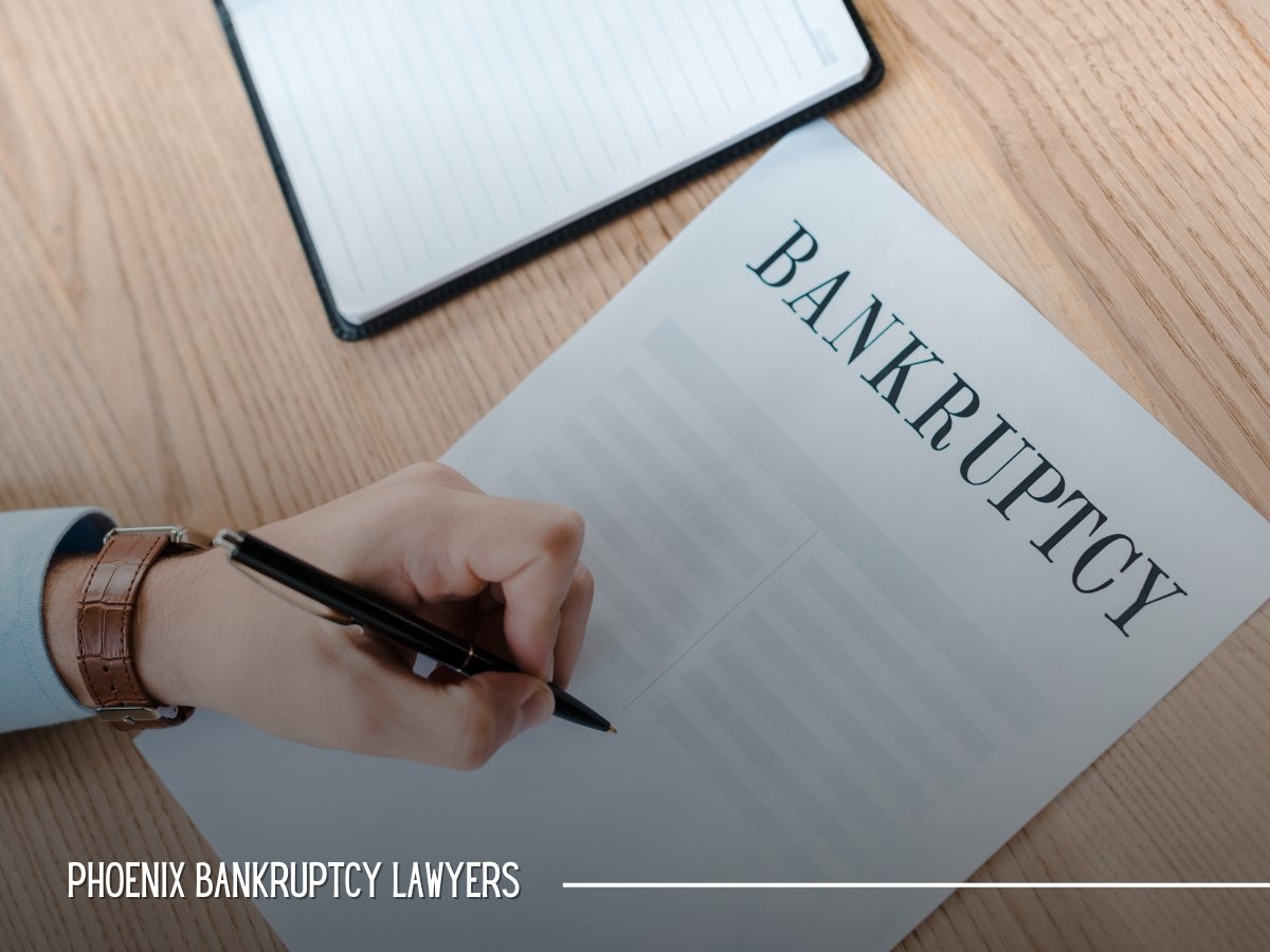 Person signing bankruptcy paperwork at a desk in Phoenix, AZ